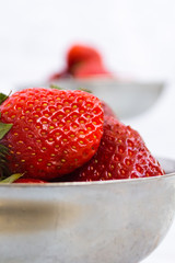 Bright ripe strawberry in a metal cups on a light background.