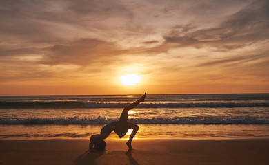 Girl on the beach during sunset doing yoga