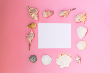 Fototapeta na wymiar Empty white sheet of paper for text on a pink background. Background with shells and pebbles.