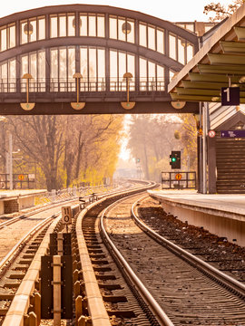 View along the tracks in the S-Bahn station Buckower Chaussee in Berlin, Marienfelde. The atmosphere is determined by the orange sunlight on a hazy day.