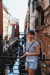 Obraz na płótnie Canvas Young woman tourist standing on a bridge near rio del Vin canal in Venice, Italy. Travel concept