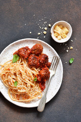 Spaghetti pasta with meatballs, tomato sauce and parmesan on the kitchen table. View from above.