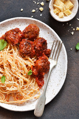 Spaghetti pasta with meatballs, tomato sauce and parmesan on the kitchen table. View from above.