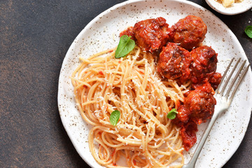 Spaghetti pasta with meatballs, tomato sauce and parmesan on the kitchen table. View from above.