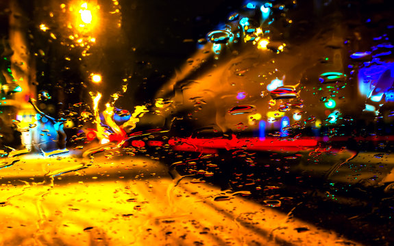 City view through blurry with heavy rain on the car window. Blured background with rains drop on glass and shop-window lengthways road. Driving in rain, rainy weather