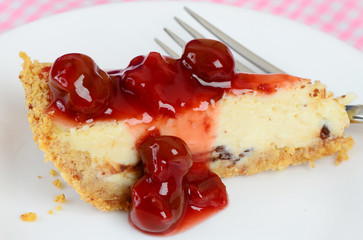 Closeup of slice of cheesecake with cherry sauce spread over top.