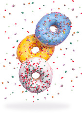 Sweet and colorful decorated donuts falling or flying in motion on an isolated white background