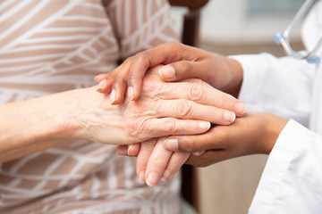 African American Hands Comforting Elderly Caucasian Hands at a Nursing Home or Elderly Care