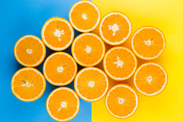 Cut halves of juicy orange on yellow blue background. Orange fruit, citrus minimal concept....