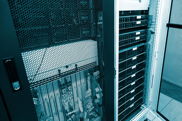 Severs computer in rack at big data center under grid door with green toning. Datacentre interface...