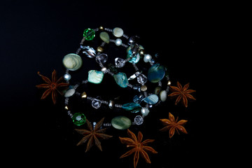 gemstone necklace and star anise on black background
