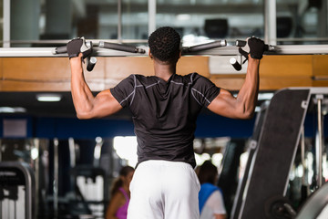 Black African American  young man doing pull up workout at the gym