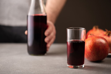 Pomegranate juice in a glass on gray background.