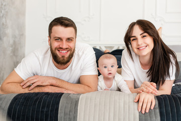 Happy smiling young family portrait in bed