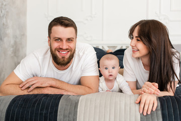 Portrait of happy young smiling family in bedroom.