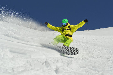 Young man flying on snowboard on powder day at blue sky background