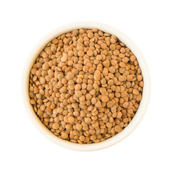 Top view of raw lentils seeds in round ceramic plate isolated on white background