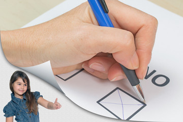 Cute tanned little girl standing in an exposed corner of the photo is pointing at a page with curl...