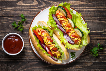 Hot dog with sausage and vegetables on wooden table.