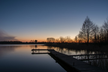Obraz premium Long jetty on a calm lake and colorful sky after sunset