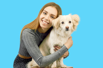 Positive female with glad expression and her dog being satisfied after walk outdoor, have good relationships, isolated over blue background. Domestic animals and people 