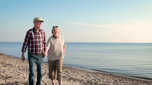 fr&ouml;hliches, gl&uuml;ckliches, verliebtes Rentner Ehepaar, Senioren gehen am Strand spazieren. Alte Frau, alter Mann