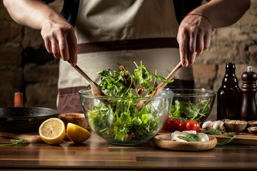 Cooking diet salad with fresh vegetables and cheese by chef cook hands on background with ingredients.