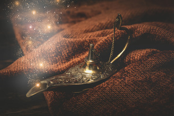 A golden Genie lamp on a table cloth background.