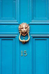House door number fifteen with the 15 in bronze on a turquoise door with lion head door knocker