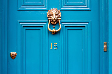 House door number fifteen with the 15 in bronze on a turquoise door with lion head door knocker