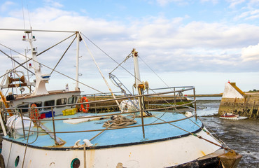 A fishing boat in the port of Saint-Vaast-la-Hougue at low tide . Normandy, France