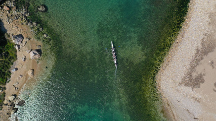 Aerial drone bird's eye view of sport canoe operated by team of young women in tropical caribbean exotic island with emerald and sapphire clear sea
