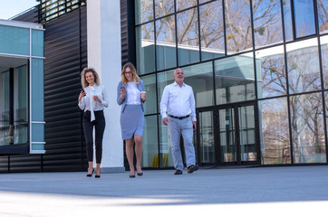 Group of business people walking outdoor in front of an office building