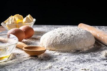 Fototapeta na wymiar White flour with eggs, butter and dough on a cooking board
