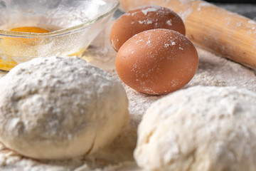 Fototapeta na wymiar White flour with eggs, butter and dough on a cooking board
