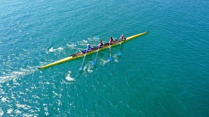 Aerial drone bird's eye view photo of yellow sport canoe operated by team of young team in emerald...