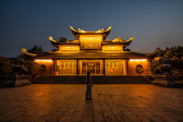 A woman poses in front of a Buddhist temple in Vietnam.  Bai Dinh Pagoda