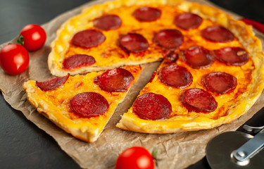 Tasty pepperoni pizza of tomatoes and ingredients on concrete background.