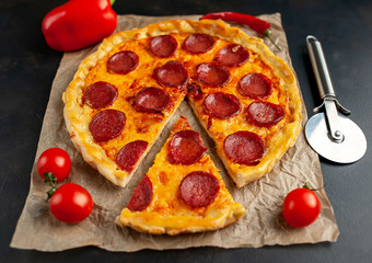 Tasty pepperoni pizza of tomatoes and ingredients on concrete background.
