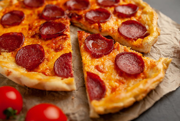 Tasty pepperoni pizza of tomatoes and ingredients on concrete background.