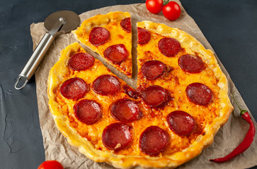 Tasty pepperoni pizza of tomatoes and ingredients on concrete background.
