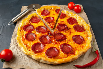 Tasty pepperoni pizza of tomatoes and ingredients on concrete background.