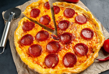Tasty pepperoni pizza of tomatoes and ingredients on concrete background.