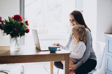 Young mother and her little daughter sitting using a laptop