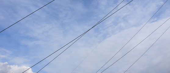 Fototapeta premium Stromleitungen vor blauen Himmel mit weißen Wolken
