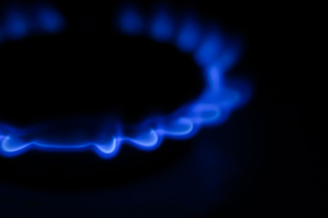 Gas burner. Burning blue gas on the stove on dark background. 