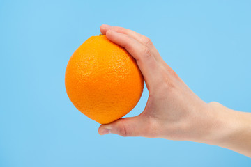 Hand holding organic delicious orange Isolated on blue Background. Healthy eating and dieting concept