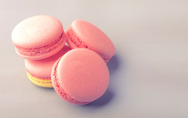Pink yellow macaroons cakes on gray blue table background, place for text, trendy minimalism style, selective focus