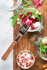 Beet or beetroot salad with fresh arugula, soft cheese and walnuts, trendy salad jar, piece on a fork, gray kitchen table background, copy space, top view