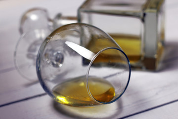 Glass with alcohol with blurred carafe on white wooden background.  Part of set.